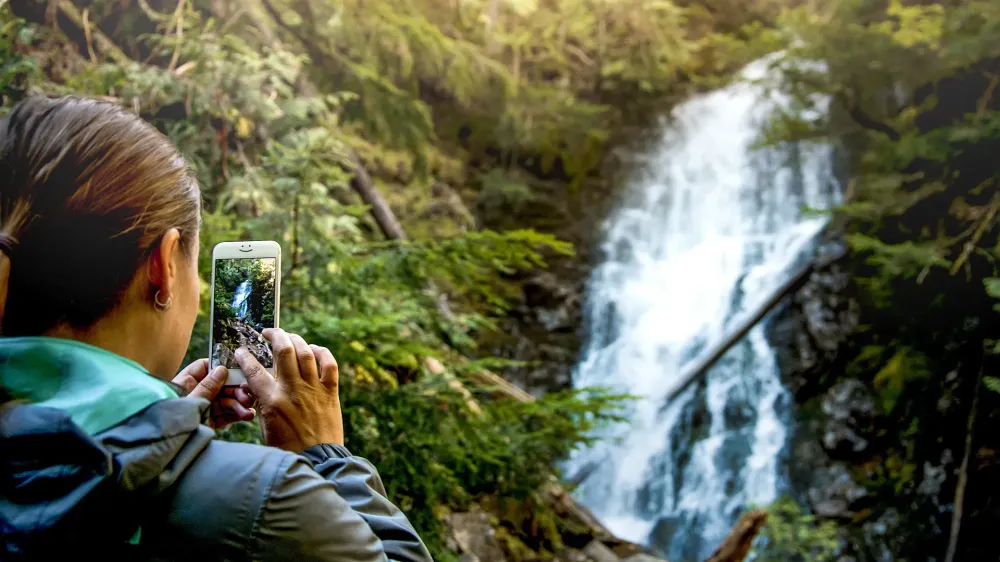 person taking photo or video of waterfall smartphone iphone